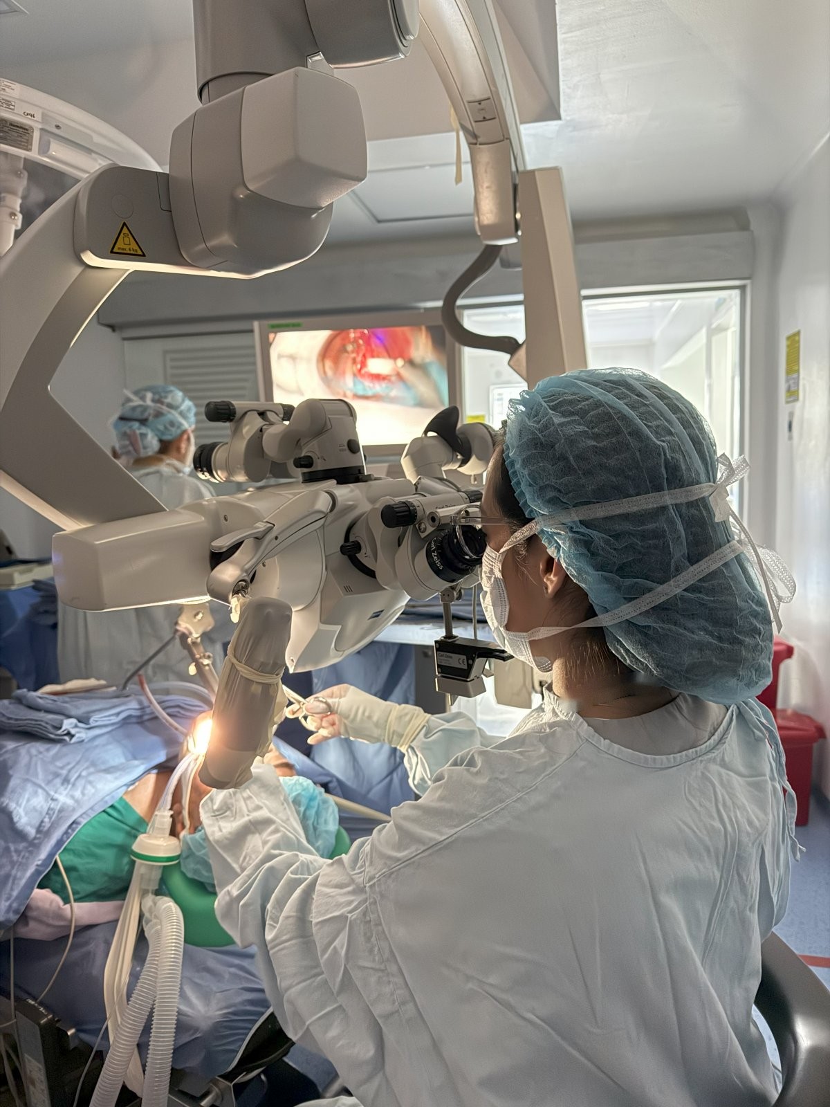 La doctora opera a través del microscopio quirúrgico mientras la imagen se proyecta en un monitor